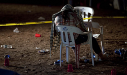 Covered by a shirt, the body of Claudia Mora sits on a chair where she was murdered at a race circuit on the outskirts of Ciudad Juarez by Juarez drug cartel. (Photo by Guillermo Arias/AP)